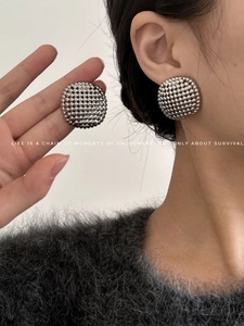 Macro detail of silver spherical stud earrings with dense cluster bead texture on model