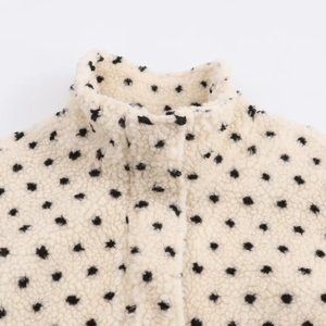 Détail d'une veste en polaire à pois noirs avec col montant et texture douce et épaisse