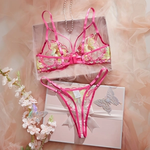 Flat lay of pink lace lingerie set with floral embroidery and pearls on a gift box