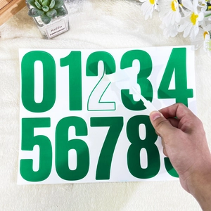 Peeling a glossy green 4 inch number 2 sticker from a set for mailboxes and bins