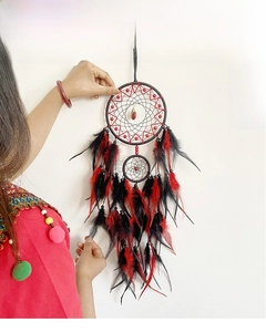 Detail of red and black handmade dreamcatcher feathers hanging on a white wall