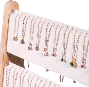 Close-up of gold pendant necklaces with charms on a beige velvet jewelry display stand