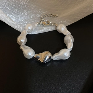 Gros plan d'un bracelet en perles baroques irrégulières avec un accent en métal argenté