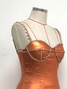 Detail eines orangefarbenen Metallic-Kleides mit Strasssteinen an Trägern und Ausschnitt
