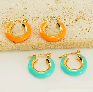 Detail view of retro gold-plated C-shape hoop earrings in orange and mint green enamel