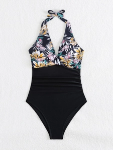 Detail of floral halter neck one-piece swimsuit with ruched slimming black bottom