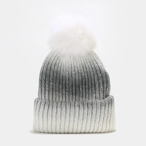 Détail du bonnet en maille dégradée avec texture côtelée et pompon en fausse fourrure
