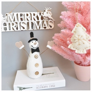 Detail of white wool felt snowman with black top hat and wooden buttons for Christmas
