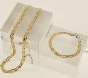 Detailed view of woven three-tone herringbone chain necklace and bracelet jewelry set