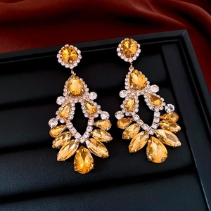 Macro shot of vintage style amber rhinestone teardrop earrings on a black display tray