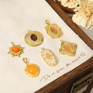 Detailed flat lay of assorted vintage bohemian gold-plated stone pendants on white linen