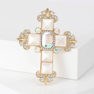 Baroque golden cross brooch with white pearls and rhinestones on a white geometric base