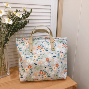Detailed close-up of floral tote bag with blue fabric, orange flowers and leather handles