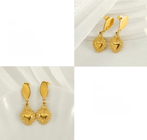 Close-up of gold heart earrings with vintage embossed textures and polished oval studs