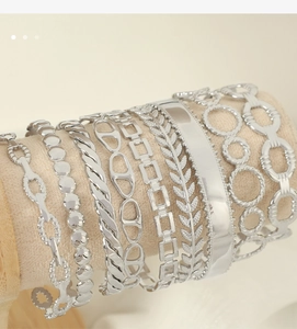 Detailed close-up of mixed silver vintage Cuban chain bracelets and hollow C-shaped bangles