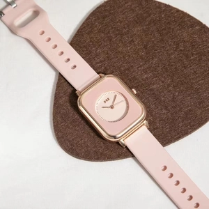 Detail of pink rectangular watch dial with rose gold case and soft silicone strap