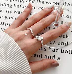 Close-up of 925 sterling silver knotted and wavy ring set worn by model on a hand