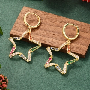 Detail of star-shaped gold earrings with colorful zircon stones on a wooden surface