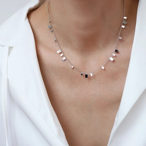 Detailed view of silver minimalist bead chain necklace with rectangular pendants on collarbone