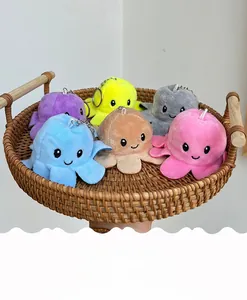 Close-up of six colorful reversible octopus plush keychains in a woven wooden tray