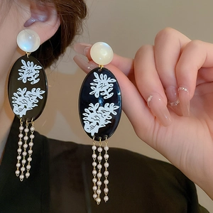 Detail of vintage flower earrings with pearl tassels shown on ear for scale and texture