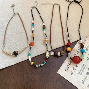 Detailed close-up of four boho beaded necklaces with stone and wood beads on linen