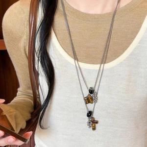 Detail of layered stainless steel necklace with tiger eye stars and cross pendants