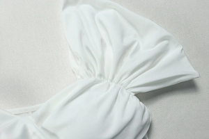 Close-up detail of white pleated fabric texture and elegant stitching on the dress