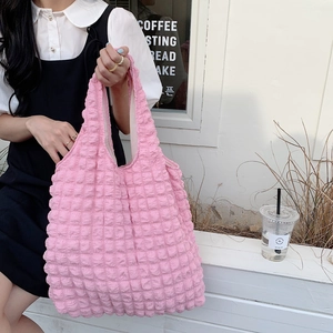 Detailed texture of pink popcorn fabric shoulder bag on a minimalist outdoor bench