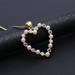 Detail of heart pendant necklace with gold plating, white pearls and colored zircon stones