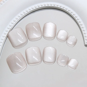 Glossy light gray cat-eye toe nail press-ons on a mirror tray with pearl accents