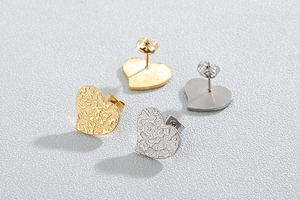 Detail of heart-shaped earrings in gold and silver with textured hammered finish