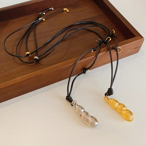 Détail des pendentifs cacahuètes dorés et argentés sur des colliers en cordon noir