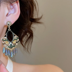 Close-up of vintage gold tassel earrings with green crystals and blue teardrop beads