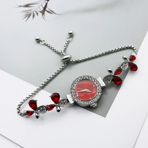 Détail d'une montre-bracelet argentée avec cadran rouge et motifs de fleurs en cristal