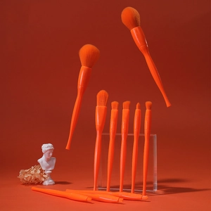 Close-up of 8 orange makeup brushes with synthetic bristles on orange background