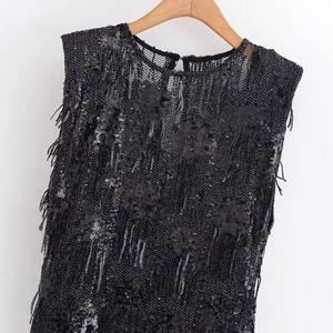 Haut élégant sans manches à paillettes noires et franges sur cintre en bois sur blanc