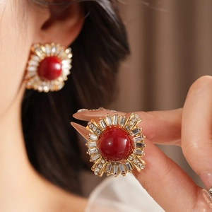 Detailed close-up of vintage gold earrings featuring red beads and sparkling zircons
