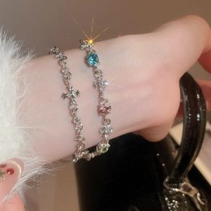 Detail of silver-tone bracelets with cross charms and colorful gemstones on a wrist
