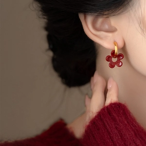 Boucles d'oreilles vintage avec pendentif fleur rouge et anneau doré portées par un modèle