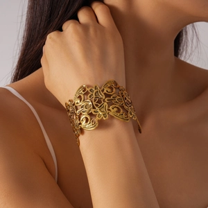 Detailed view of wide open cuff bracelet with intricate gold floral filigree design