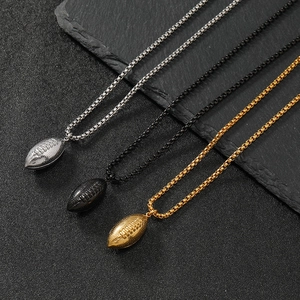 Three rugby ball pendants in silver, black, and gold on box chains against a dark texture