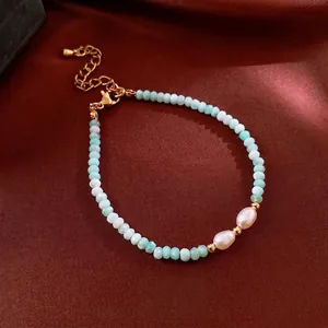 Elegant amazonite and pearl beaded bracelet with gold accents on a silk background
