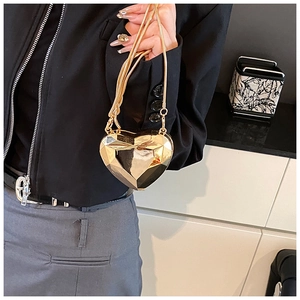 Detailed view of a heart-shaped geometric metal handbag with gold chain held by a model
