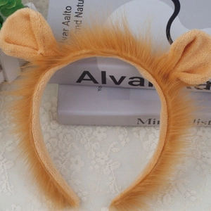Detail of plush lion ear headband for kids in orange faux fur on a lace backdrop