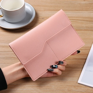 Close-up of pink PU leather passport holder with stitching detail on wooden table