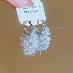 Détails de créoles argentées avec franges en cristal sur une carte à bijoux blanche