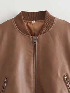 Detail view of brown leather bomber jacket showing metal zipper and ribbed neckline