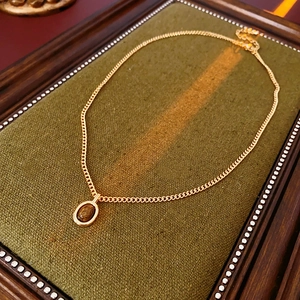 Gros plan d'un collier vintage doré avec pendentif ovale en oeil de tigre sur tissu vert