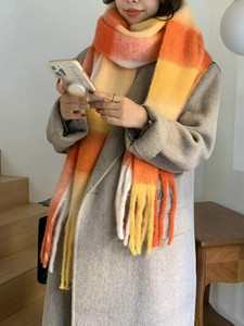Close-up of soft thick rainbow plaid scarf featuring orange and white tassels